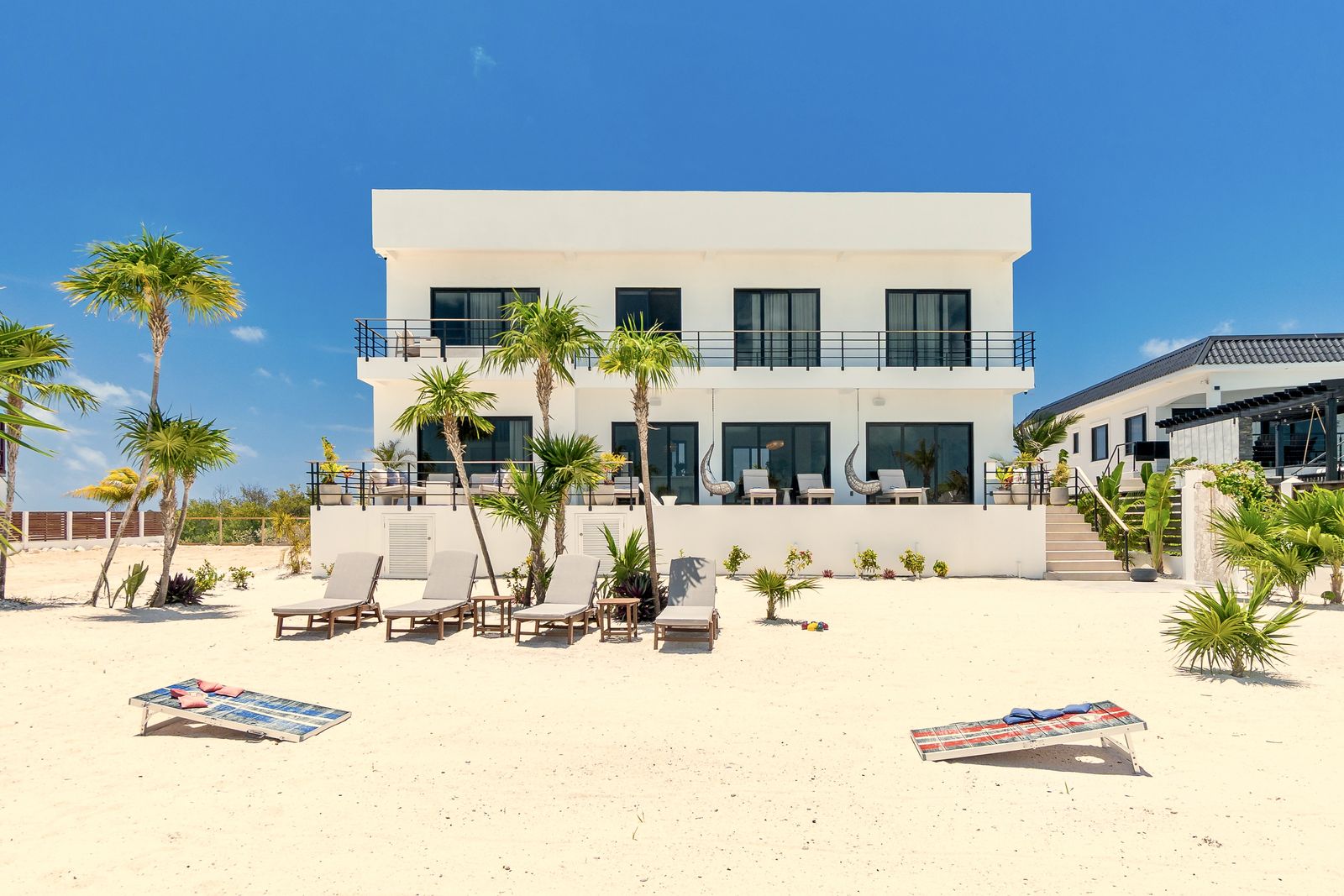 Beach loungers on the sand directly in front of the villa