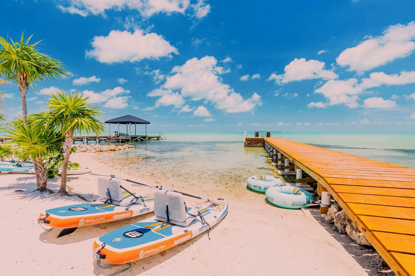 Paddleboards and kayaks on the sand beside the private dock and palapa
