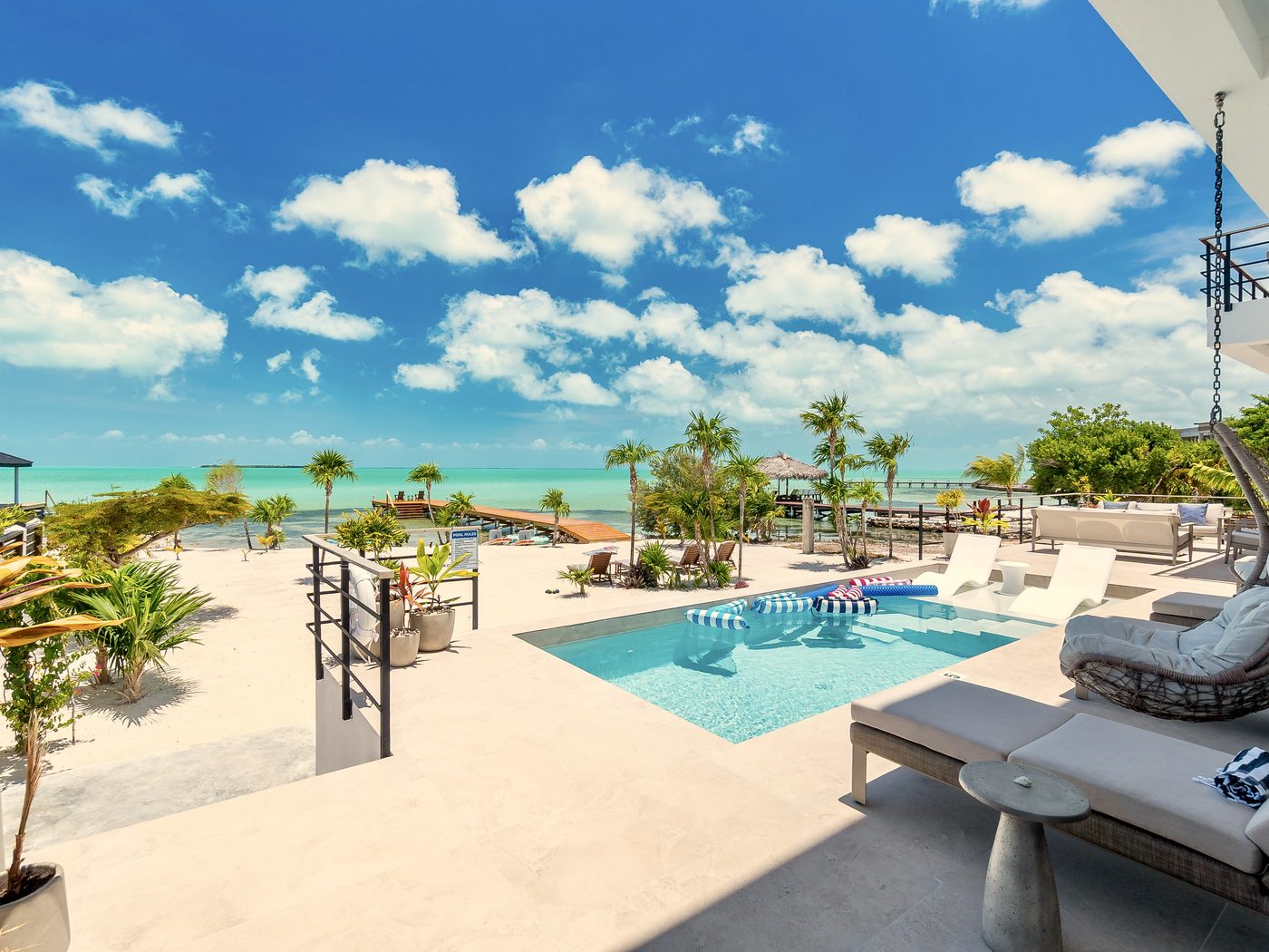 The saltwater pool and sun deck of Black Orchid Oasis, with the beach, private dock and turquoise sea beyond, Secret Beach, Belize