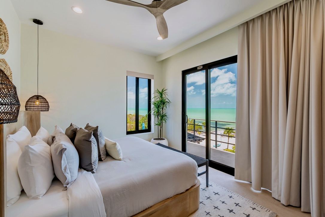 The Palm Suite: a king bed with floor-to-ceiling glass and a corner sea view