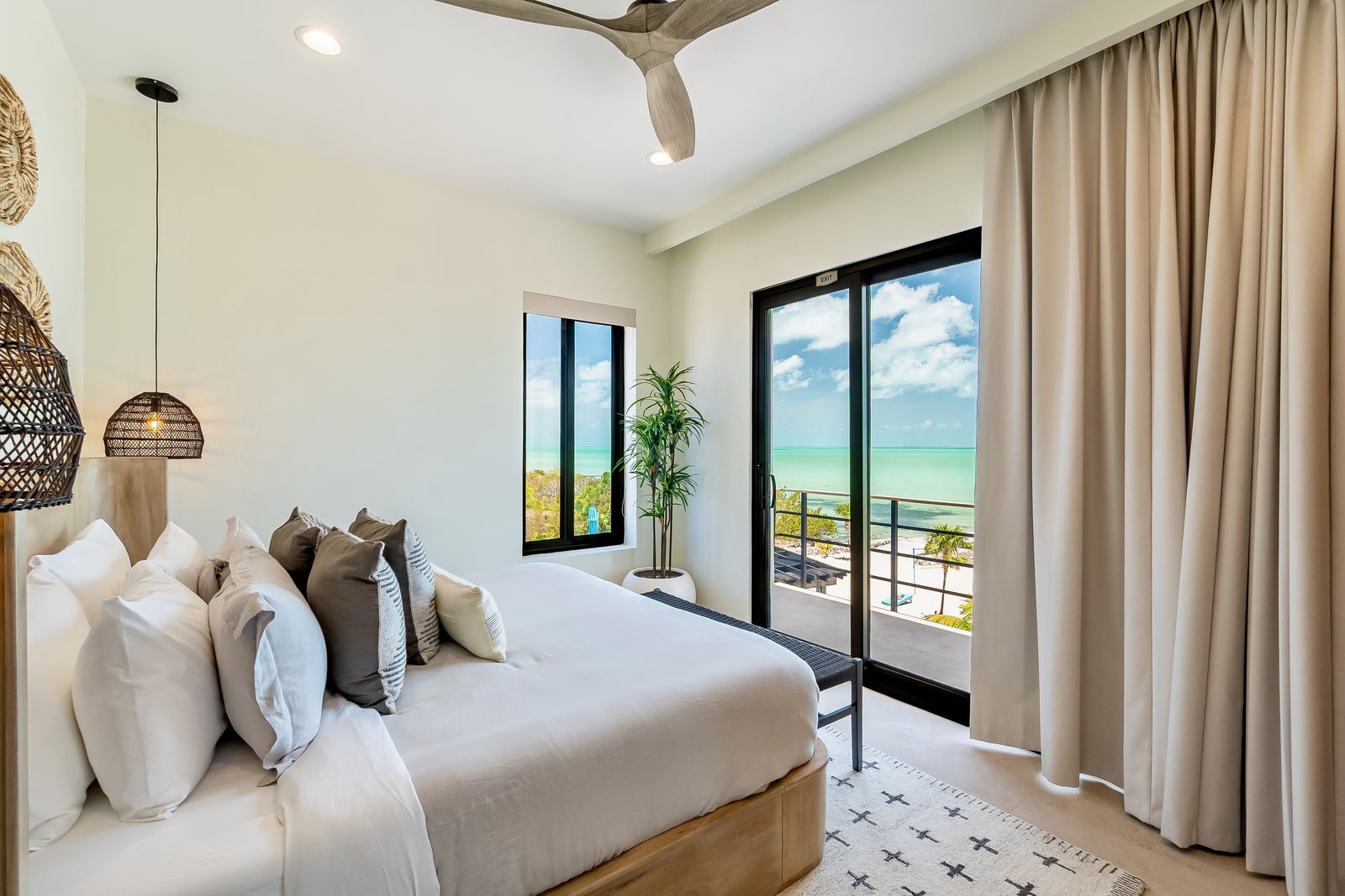 The Palm Suite: king bed with floor-to-ceiling glass and a corner window facing the sea