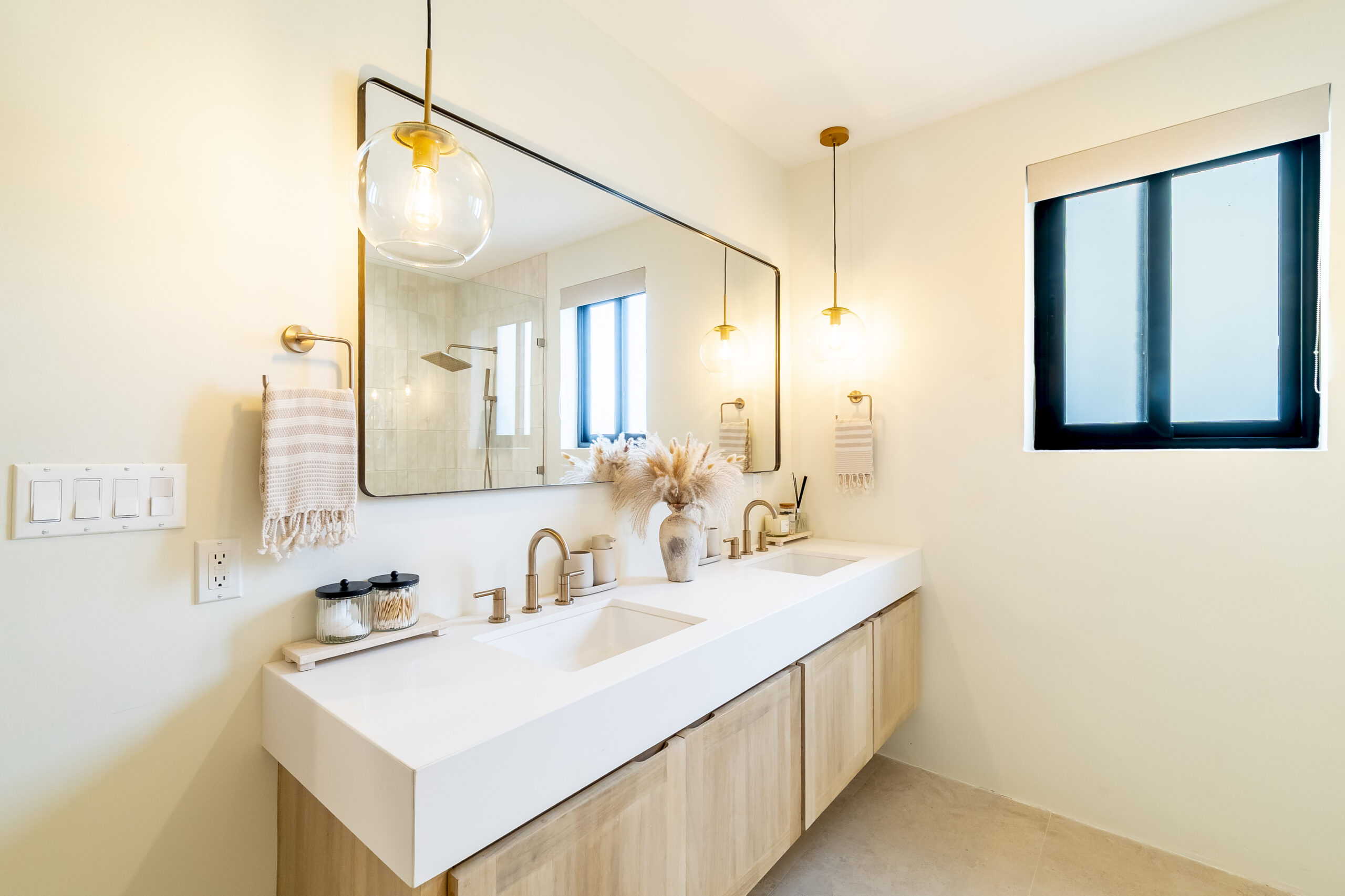 Modern luxury en-suite bathroom with double vanity, gold fixtures, and walk-in shower at Black Orchid Oasis in San Pedro, Belize.