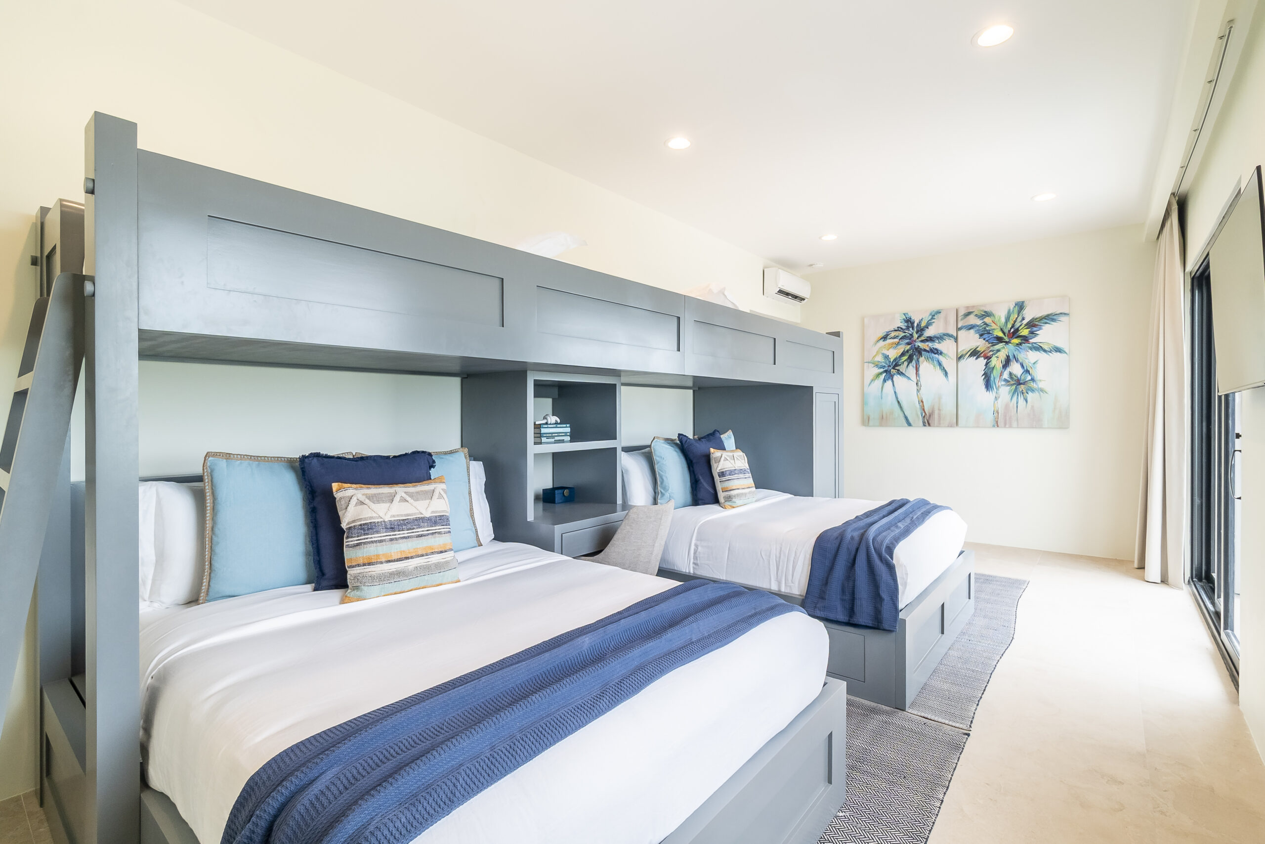 Custom luxury bunk room with queen beds and blue decor at Black Orchid Oasis in San Pedro, Belize, sleeping up to 12 guests.