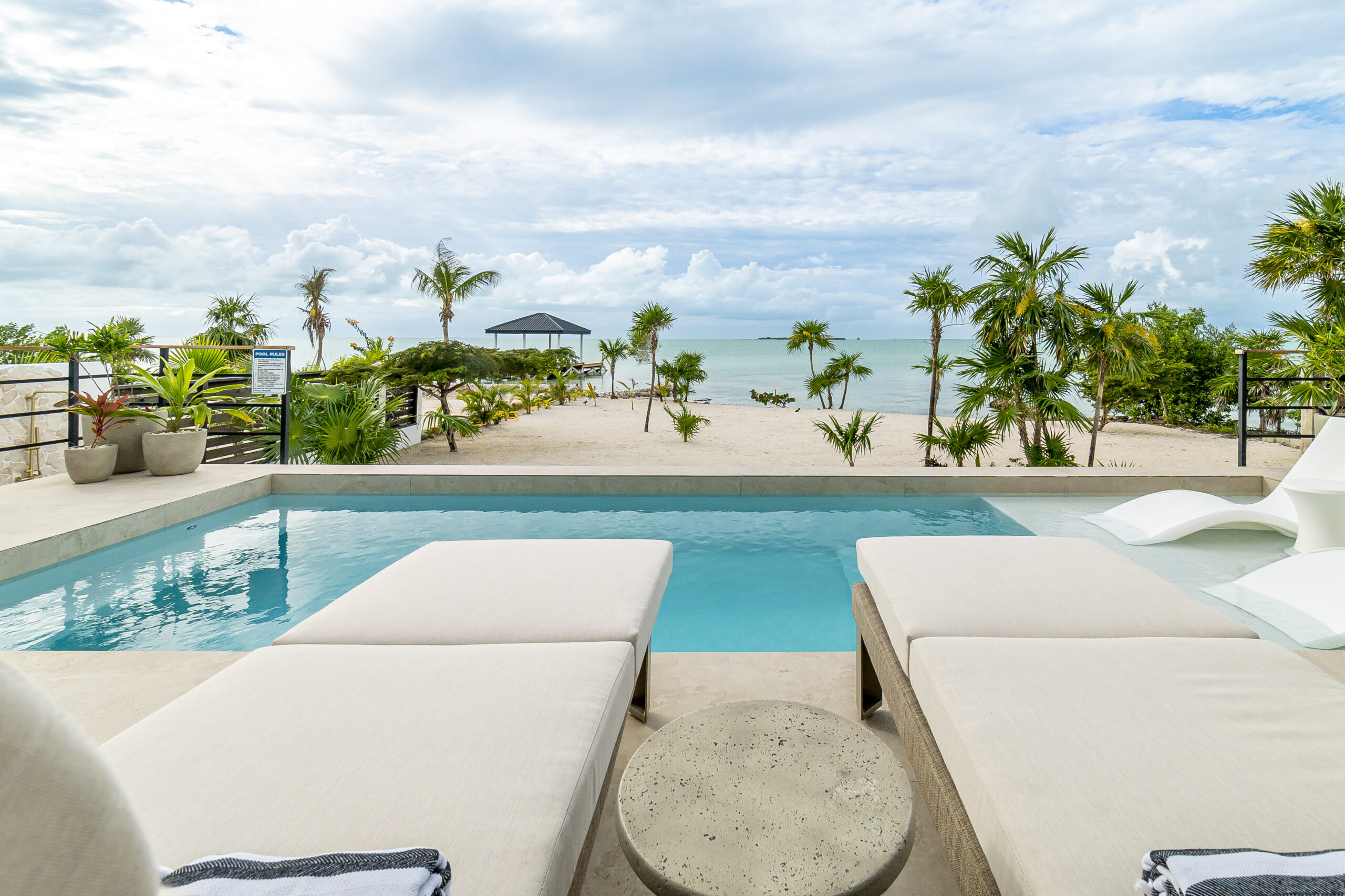 Luxury beachfront villa infinity pool with lounge chairs overlooking the ocean at Black Orchid Oasis, San Pedro Belize.