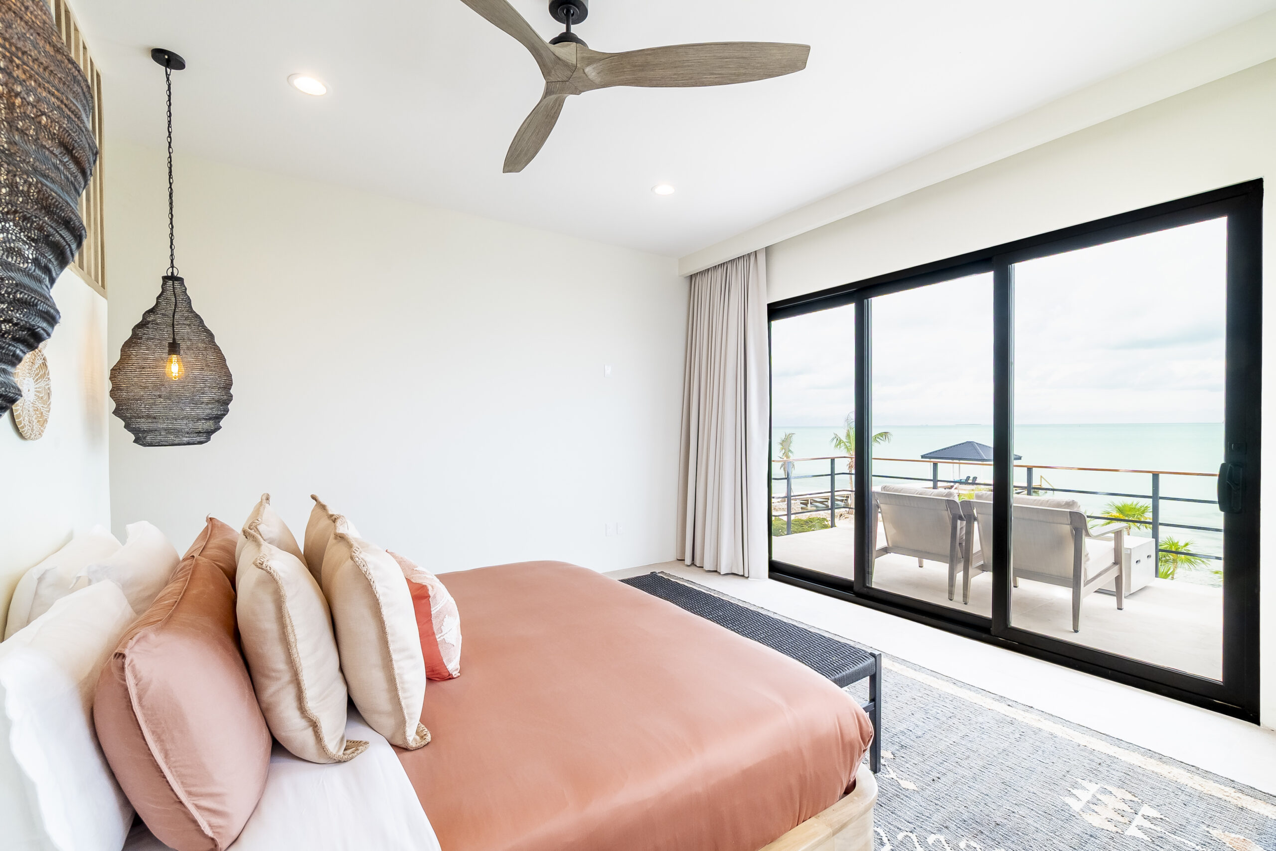 Luxury king bedroom with en-suite bathroom, oceanfront balcony, and modern tropical decor at Black Orchid Oasis in San Pedro, Belize.