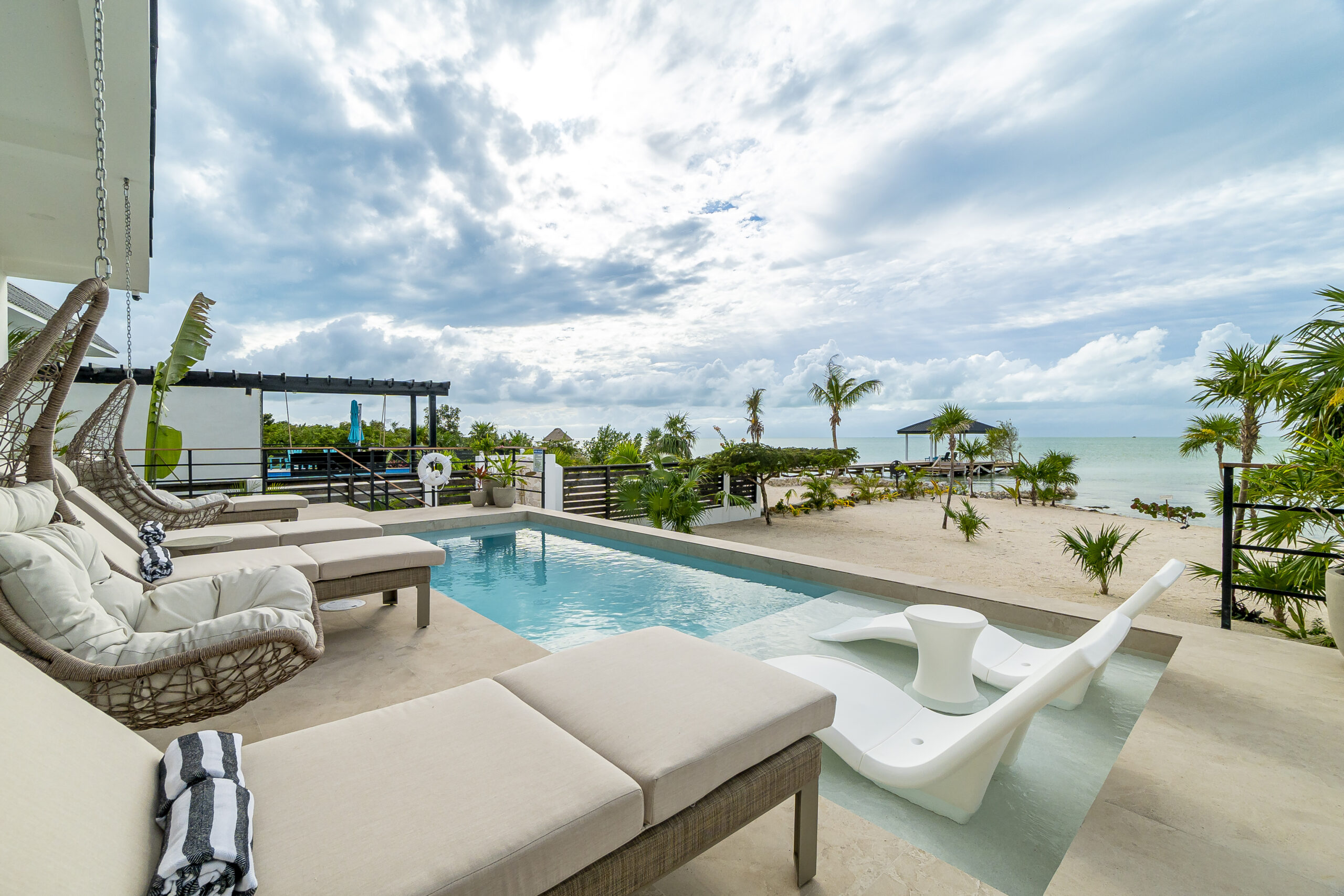 Luxury beachfront villa infinity pool with lounge chairs overlooking the ocean at Black Orchid Oasis, San Pedro Belize.